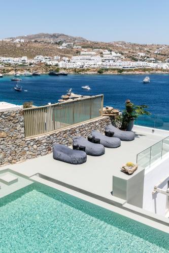 a pool with pillows and a view of the water at Villa Lilium I - Overlooking Psarou Bay, Mykonos in Psarou