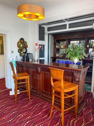 a bar with two wooden chairs and a counter at The Broadway Hotel in Llandudno