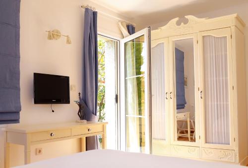 1 dormitorio con 1 cama, TV y ventana en Alacati Gubiba Evleri en Alacati