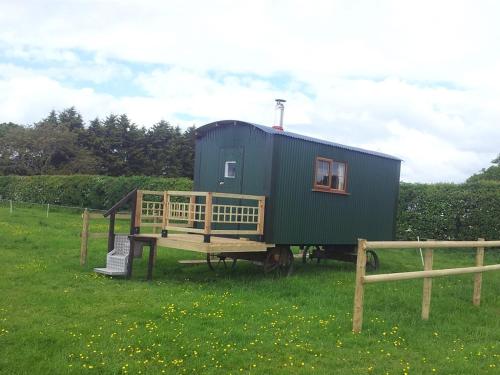 a green tiny house sitting in a field at Shepherds Lodge in Upton upon Severn