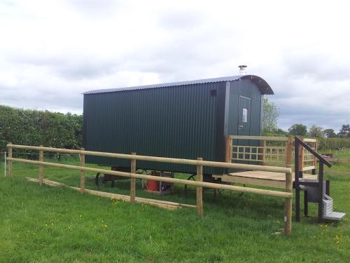 a fence with a bench in front of a building at Shepherds Lodge in Upton upon Severn