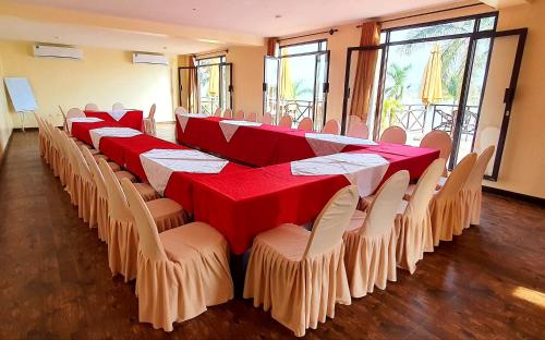 une rangée de tables et de chaises avec des nappes rouges et blanches dans l'établissement Kaazi Beach Resort, à Kampala