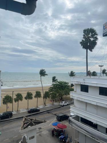 a view of a beach and a building with palm trees at อีสานจอมเทียน in Jomtien Beach