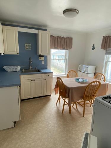 a kitchen with a table and chairs and a kitchen with blue walls at Nautical Beach Apartments in Hampton