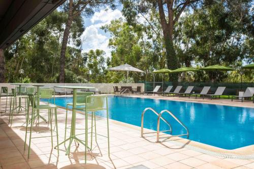 a swimming pool with green chairs and tables and chairs at Belstay Roma Aurelia in Rome