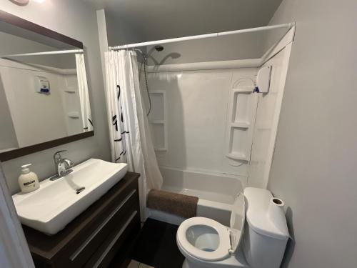 La salle de bains blanche est pourvue d'un lavabo et de toilettes. dans l'établissement Auberge Lac-Saint-Jean, à Roberval