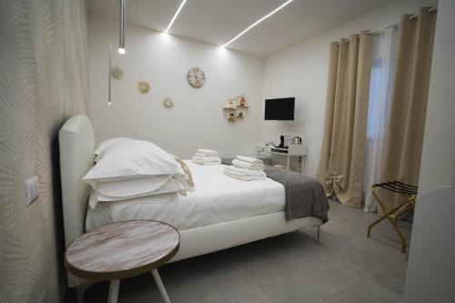a white bedroom with a bed and a table at Arco Alto Rooms in Bari