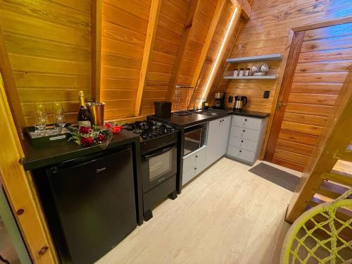 cocina con electrodomésticos negros y paredes de madera en Cabana Relax - Picada Café, en Picada Café