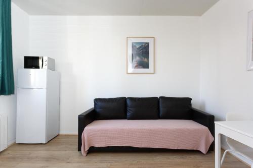 ein schwarzes Sofa in einem Zimmer mit einer weißen Wand in der Unterkunft LG fond de cour F1 in Drancy