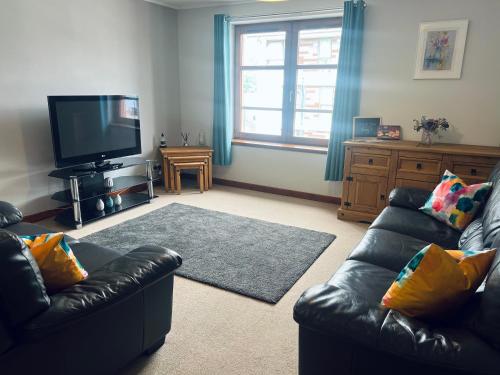 a living room with two leather couches and a flat screen tv at Waverley Court in Fort William