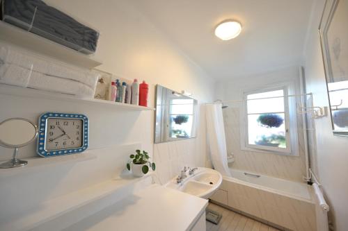 La salle de bains est pourvue d'un lavabo et d'une horloge murale. dans l'établissement Villa d'art - Claire, à Paris