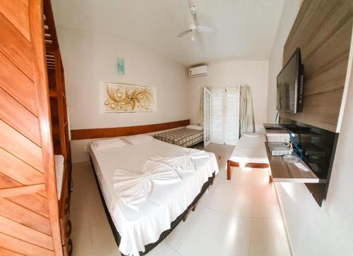 1 dormitorio con 1 cama blanca y TV en Pousada Terra Nostra, en Prado