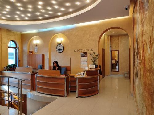 a woman sitting at a counter in a waiting room at Семеен Хотел "Булаир" in Burgas City
