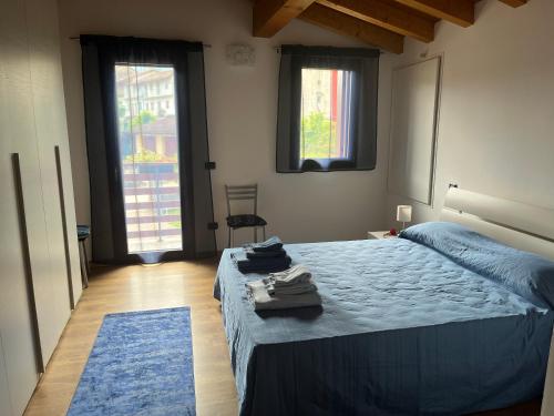 a bedroom with a bed with blue sheets and two windows at Casa Conchet in Polcenigo
