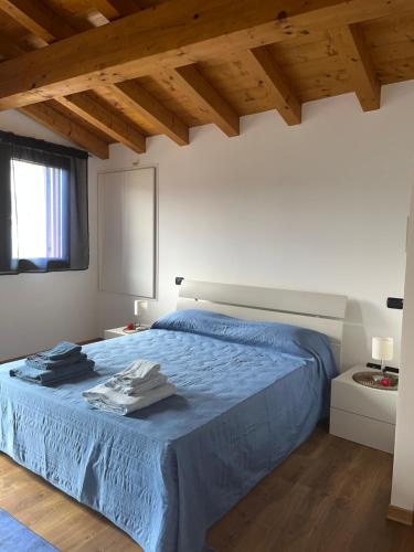 Schlafzimmer mit blauem Bett und Holzdecken in der Unterkunft Casa Conchet in Polcenigo
