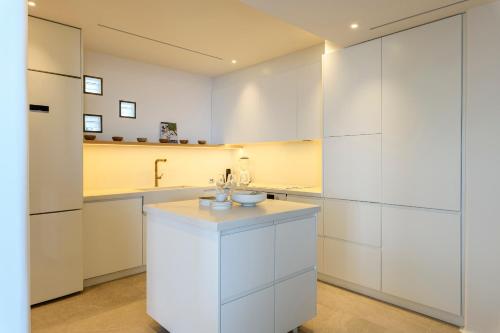 a white kitchen with white cabinets and a sink at Villa Lilium II in Psarou