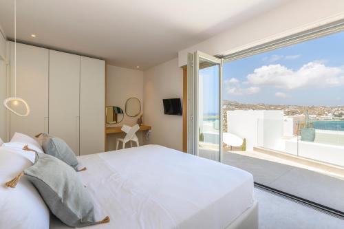 a bedroom with a white bed and a large window at Villa Lilium II in Psarou