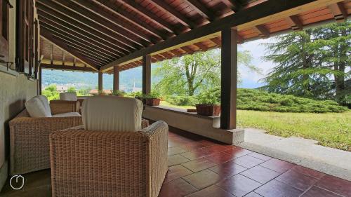 eine Veranda mit Korbstühlen und einer Pergola in der Unterkunft Italianway - San Rocco 73 in San Fedele Intelvi