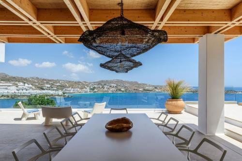 a dining room with a table and chairs and a chandelier at Villa Lilium II - Sanctuary overlooking Psarou Bay in Psarou