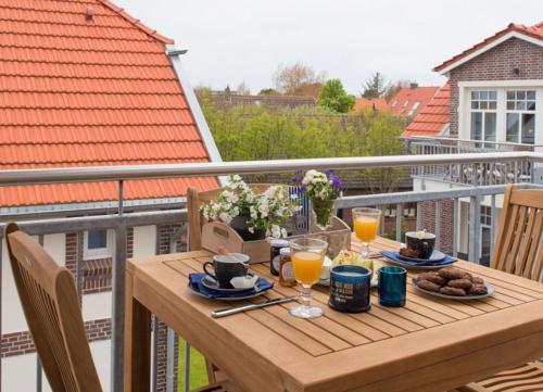 a wooden table with food and drinks on a balcony at Lindenhof - Sandperle in Wangerooge
