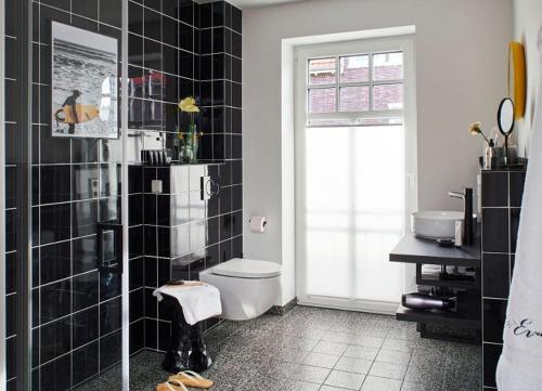a bathroom with a toilet and black tile walls at Miss Evans macht blau in Wangerooge