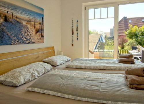 ヴァンガーオーゲにあるInselparadies - Neubauwohnung mit großer Terrasse, Strandkorb und Garten.の窓付きの客室で、ベッド2台が備わります。