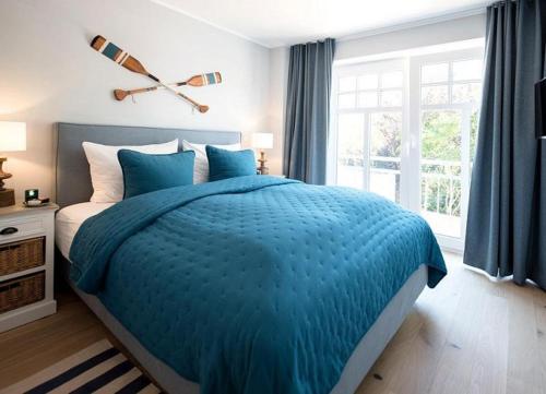 1 dormitorio con cama azul y ventana grande en Lindenhof- Silbermöwe, en Wangerooge