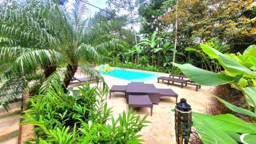 a pool with a table and benches and trees at La Semilla Ecolodge in Cerro Azul