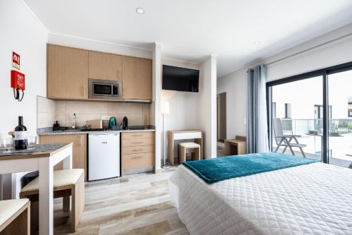 a bedroom with a bed and a kitchen with a table at CASA DAS PRAIAS in Lagos