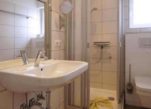 ein weißes Badezimmer mit Waschbecken und Dusche in der Unterkunft Meike 2 - Ebenerdige Wohnung mit Terrasse und kleinem Garten in Wangerooge