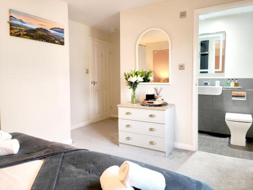 a white bedroom with a white dresser and a bathroom at Yewtree House in Penrith