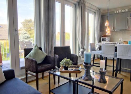 - un salon avec un canapé, des chaises et une table dans l'établissement Strandvogt - wunderschöne Ferienwohnung mit Parkettboden und Sonnenbalkon, à Wangerooge