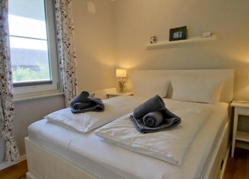 - un lit blanc avec des serviettes et une fenêtre dans l'établissement Strandvogt - wunderschöne Ferienwohnung mit Parkettboden und Sonnenbalkon, à Wangerooge