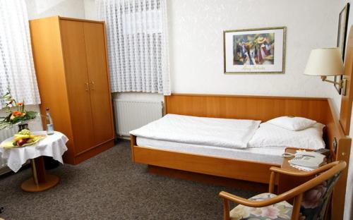 a small bedroom with a bed and a table at Hotel Restaurant Pempel in Großalmerode
