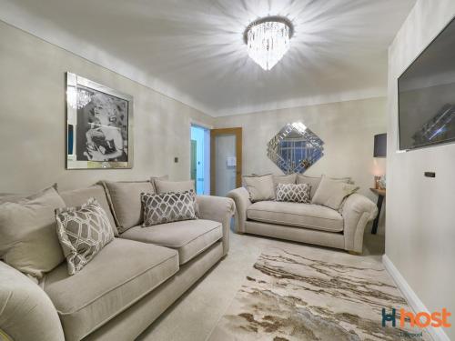 a living room with two couches and a chandelier at Host Liverpool - Greasby Luxury Home, Near Golf & Beach in Greasby