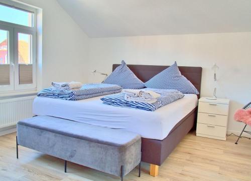 a large bed with a ottoman in a bedroom at WoogeElisa - Ehrwürdige Dorfvilla in Strandnähe in Wangerooge