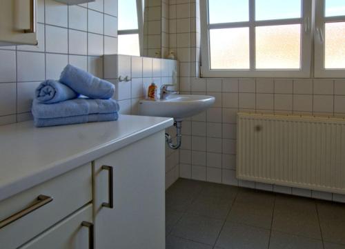 a white bathroom with a sink and a towel at Sonnenstern - Sonnenverwöhnte Familienwohnung mit Balkon in Wangerooge