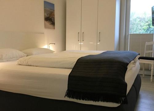a bedroom with a bed with a black blanket on it at Robby 7 - Hundefreundliche Terrassenwohnung mit eigenem Garten in Wangerooge