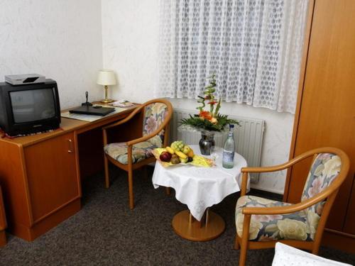 Habitación con escritorio y mesa con fruta. en Hotel Restaurant Pempel en Großalmerode