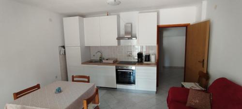 a kitchen with white cabinets and a table and a table and a dining room at Apartment Kurelic in Rab