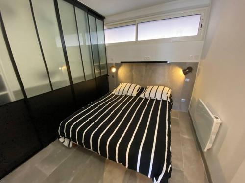 - une chambre avec un lit avec des draps rayés et une fenêtre dans l'établissement Appart 113, Port Ambonne au village naturiste, au Cap d'Agde