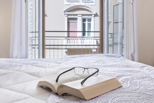 um par de óculos sentados num livro numa cama em Daddi rooms & apartment em Cagliari