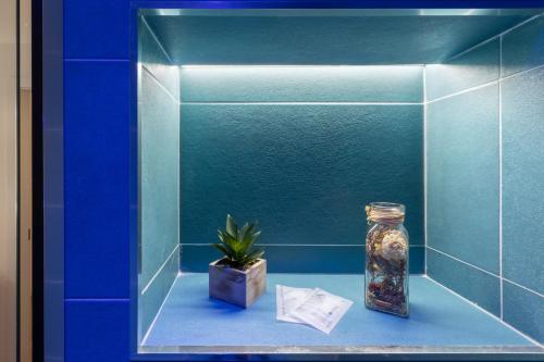 a blue tiled wall with a jar and a plant at Daddi rooms & apartment in Cagliari
