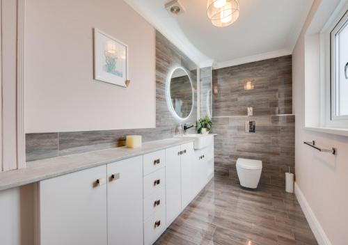 a bathroom with white cabinets and a mirror at Swallows Return in Camrose