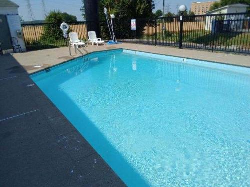 una gran piscina azul con 2 sillas blancas en Howard Johnson by Wyndham Clarksville Tennessee, en Clarksville