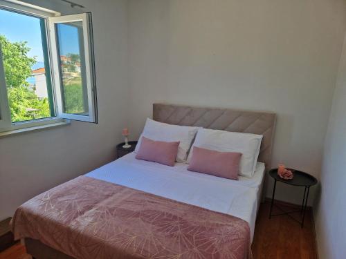 ein Schlafzimmer mit einem großen Bett mit zwei rosa Kissen in der Unterkunft Holiday Home Nino with amazing swimming pool in Slatine