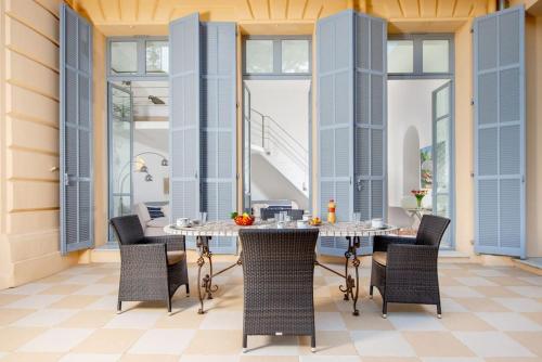 een patio met 2 tafels, stoelen en ramen bij Luxurious Historical Suite 2BDR Pool Tennis Private Beach in Roquebrune-Cap-Martin