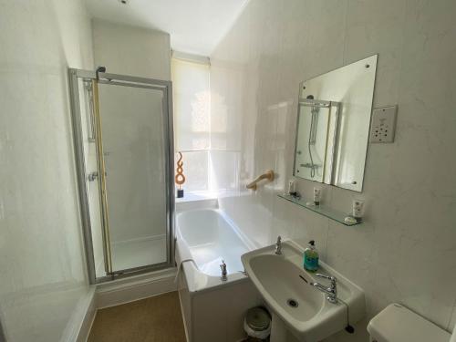 a white bathroom with a shower and a sink at The Broadway Hotel in Llandudno
