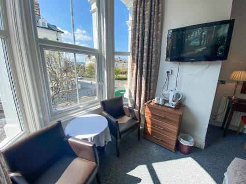 a room with a tv and a chair and a table at The Broadway Hotel in Llandudno