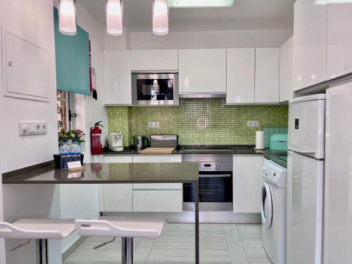 Una cocina con gabinetes blancos y un refrigerador. en The Old Village Studio Vilamoura, en Vilamoura